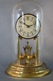 Reloj Alemn, metal dorado con fanal de vidrio, pndulo giratorio. . 31 cm.