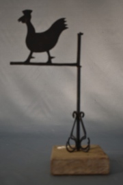 PEQUEA VELETA, de metal pintado de negro con figura de gallina. Con base de madera. Alto total: 26 cm.