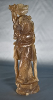 Personaje portando hojas y caja, talla china en piedra blanda. Alto: 35 cm.