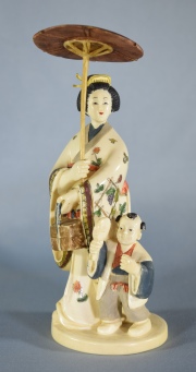 MUJER JAPONESA CON NIO Y SOMBRILLA, figura de marfil tallado y policromado. Faltantes. Al dorso firmado. Alto: 15,5 cm.