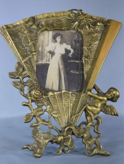 PORTA RETRATO, en forma de abanico de bronce dorado y ornado con ngel y flores. Alto: 27 cm.