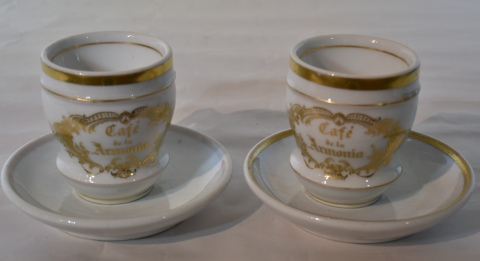 Dos tazas con plato de porcelana, Isabelina con inscripcin 'Caf De La Armonia'. Alto 12 cm.